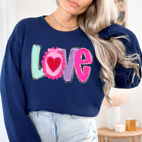 Whimsical Love DTF Heat Transfer, colorful and playful multicolored letters spelling 'LOVE' with a heart inside the 'O' on a navy blue sweatshirt.