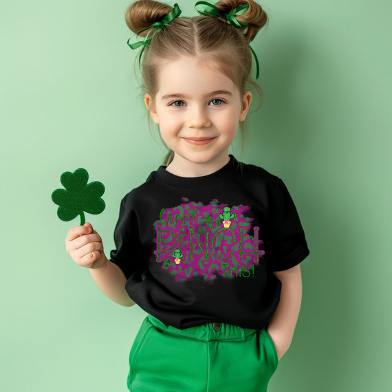 Can't Pinch This Leopard DTF Heat Transfer, young girl holding a green shamrock while wearing a black T-shirt with colorful text and graphics, celebrating St. Patrick's Day with festive attire.