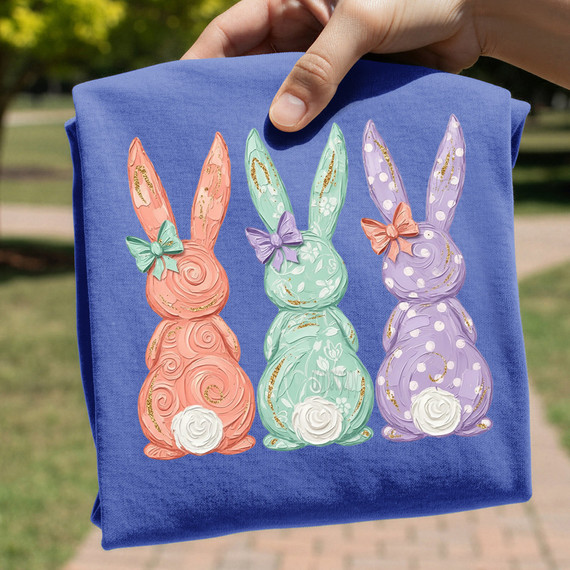 Coquette Bunny Trio DTF Heat Transfer, colorful bunny designs with bows and gold detailing on a blue fabric background.
