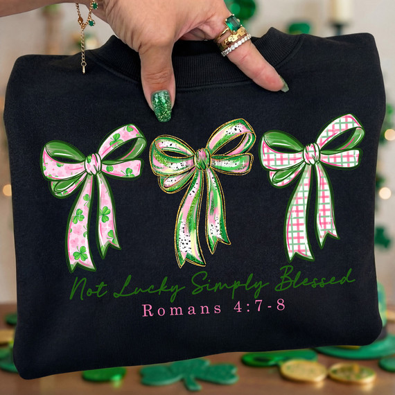 Not Lucky, Simply Blessed Bows DTF Heat Transfer on a black shirt with floral and plaid design bows, and the text 'Not Lucky Simply Blessed Romans 4:7-8' in green and pink.
