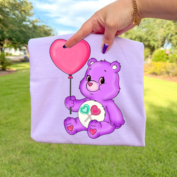 Retro Lollipop Bear DTF Heat Transfer, a cute purple teddy bear holding a pink heart-shaped balloon.