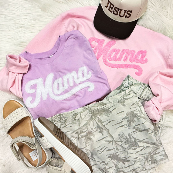 Mama Fluffy Patch, pink and purple clothing with Mama text, cap, and sneakers on a soft surface.