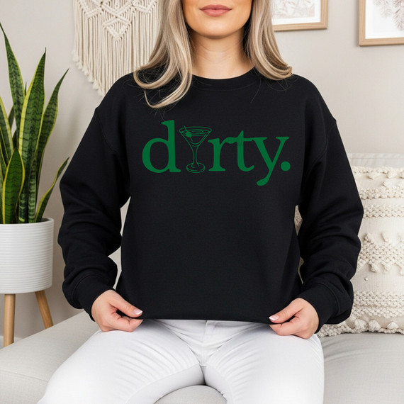 Dirty. Martini DTF Heat Transfer, black sweatshirt with green 'dirty.' text and martini glass graphic, on a woman sitting indoors.