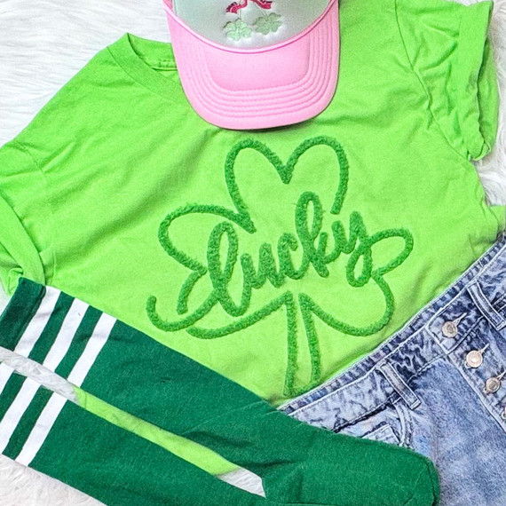 Lucky Fluffy Chenille Shamrock Patch, bright green shamrock patch with fluffy texture and the word 'Lucky' embroidered inside, on a neon green t-shirt.