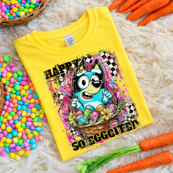Happy Easter So Eggcited DTF Heat Transfer, yellow t-shirt with colorful Easter-themed cartoon design of a chick with eggs in a basket, surrounded by flowers and vibrant paint splashes.