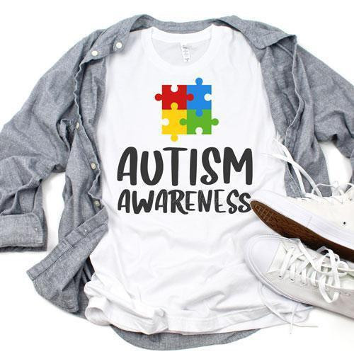 Autism Awareness Sublimation Transfer, T-shirt with colorful puzzle piece design and text, laid on a gray shirt with sneakers.