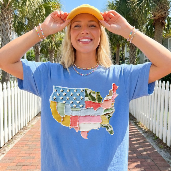 Faux Fabric Patchwork USA DTF Heat Transfer, colorful patchwork map of the United States on a blue t-shirt worn by a smiling woman outdoors.