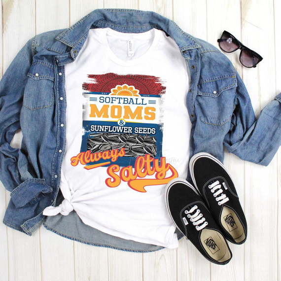 Softball Moms and Sunflower Seeds Always Salty Sublimation Transfer, graphic design on a white T-shirt, paired with a denim jacket, black Vans sneakers, and sunglasses, laid on a wooden surface.