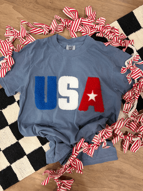USA Fluffy Patch T-shirt, blue casual T-shirt with 'USA' in fluffy patch letters, with a star inside the 'A', surrounded by red and white striped ribbons.