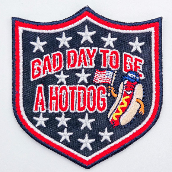 Bad Day to Be a Hotdog Shield Embroidered Patch – Patriotic Statement Patch for Hat Bars & Boutiques, featuring a hotdog with an American flag, stars, and bold red text on a navy background.