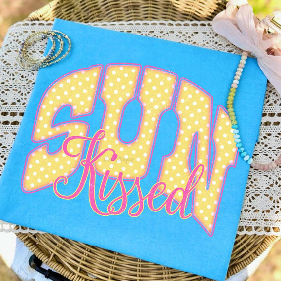 Sun Kissed Retro DTF Heat Transfer with yellow polka dot design, pink outline, and pink cursive text reading 'Kissed' on a blue fabric background.
