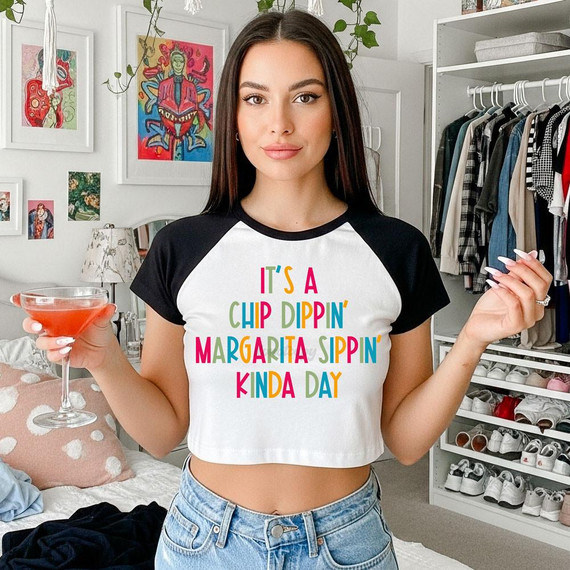 It's A Chip Dippin' Margarita Sippin' Kinda Day DTF Heat Transfer, a woman holding a margarita glass in her left hand and showcasing a white and black cropped t-shirt with colorful text.