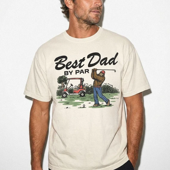 Best Dad By Par Sasquatch DTF Heat Transfer, a graphic T-shirt featuring a cartoon bigfoot playing golf.