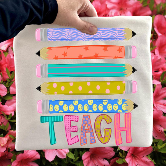 Teach Pencils DTF Heat Transfer, colorful and patterned pencil illustrations with the word 'TEACH' on a fabric surface.