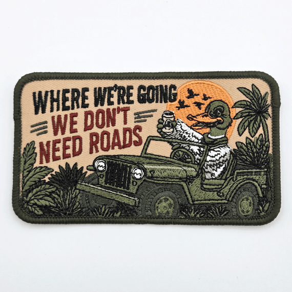 Where We're Going, We Don't Need Roads Hat Patch – 4.5 x 2.5 inches, embroidered patch featuring a humorous design with a duck driving a jeep, palm trees, and a sunset background.