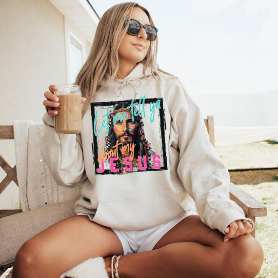 Let Me Tell Ya About My Jesus DTF Heat Transfer, a colorful graphic design of Jesus with a message, worn on a hoodie by a woman holding iced coffee outdoors.