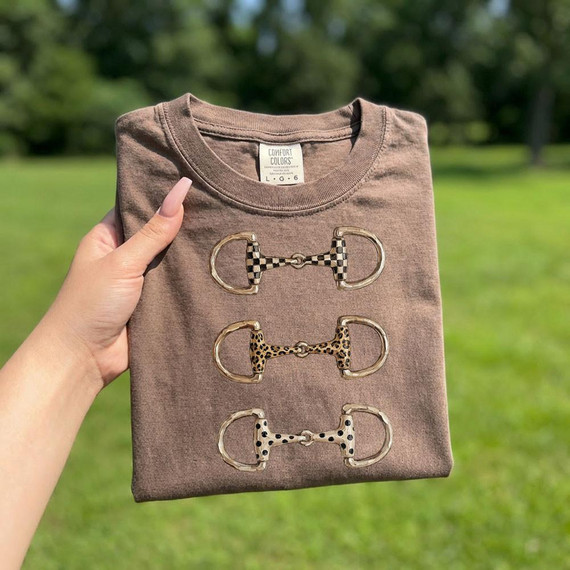 Western Horse Bit Trio DTF Heat Transfer, three decorative horse bit designs with different animal prints on a folded brown T-shirt.