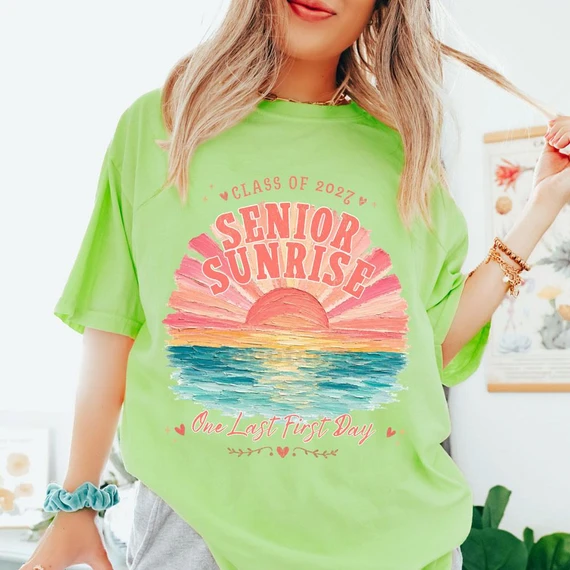 Class Of 2027 Senior Sunrise DTF Heat Transfer, a vibrant green T-shirt featuring a colorful sunset design with the words 'Senior Sunrise' and 'One Last First Day' for graduation celebration.