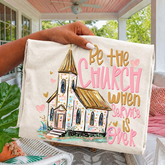 Be The Church When Service Is Over DTF Heat Transfer, a colorful illustration of a church with pink, gold, and pastel accents, surrounded by decorative hearts, displayed on a fabric with a hand holding it.