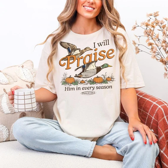 I Will Praise Him In Every Season Fall DTF Heat Transfer, a woman wearing a cream T-shirt with fall-themed ducks, pumpkins, and scripture design.
