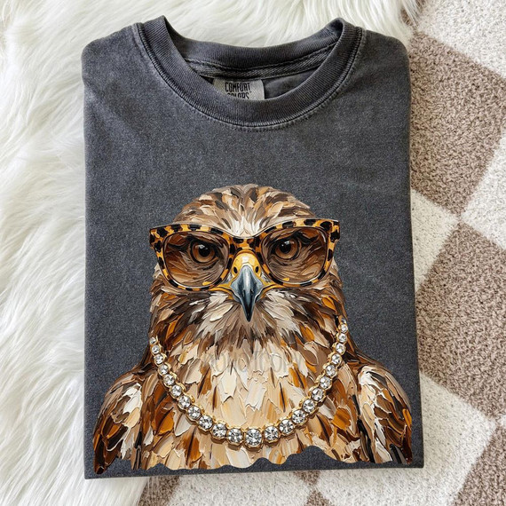 Glam Hawk DTF Heat Transfer, a stylish graphic of an eagle wearing glasses and a pearl necklace on a gray T-shirt.