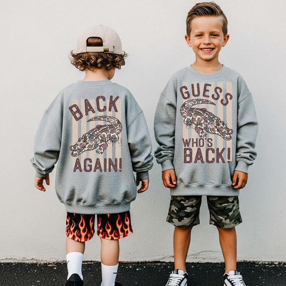 Guess Who’s Back Back Again Camo Alligator DTF Heat Transfer, image of two young boys wearing matching gray sweatshirts with a crocodile and text design, one facing away and the other smiling.