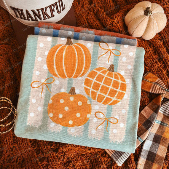 Polka Dot Plaid & Stripe Pumpkins DTF Heat Transfer, autumn-themed fabric with orange pumpkins featuring polka dots, plaid, and stripe patterns, on a light background.