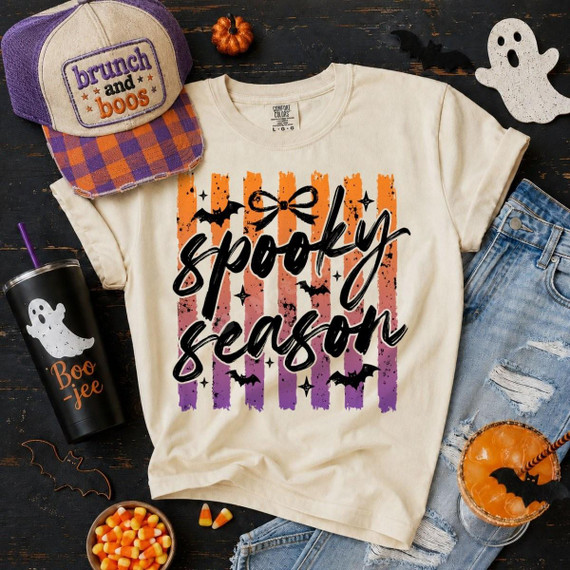 Spooky Season DTF Transfer, Retro Striped Halloween Design on a T-shirt featuring orange, purple, and black vertical stripes with bats, stars, and the text 'spooky season' in black cursive style.