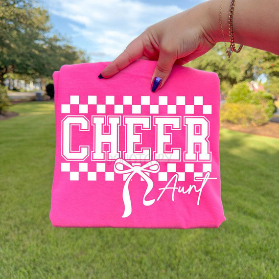 Cheer Aunt DTF Transfer | Checkerboard Bow Cheerleading Game Day Heat Transfer on pink fabric held by a hand outdoors.