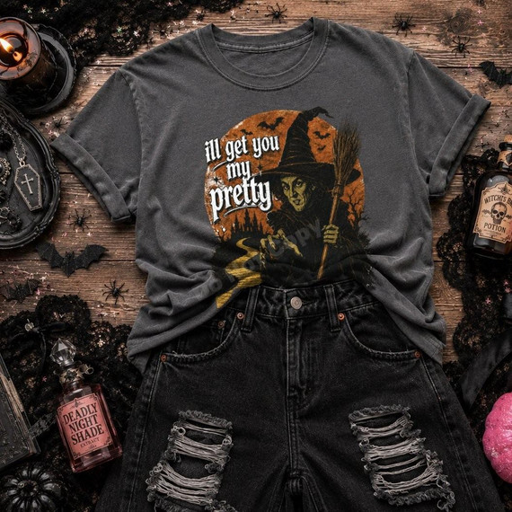 I'll Get You My Pretty Witch DTF Transfer, vintage Halloween witch design on a dark gray T-shirt pictured with Halloween decorations and distressed black jeans.