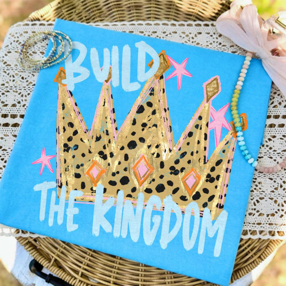 Build the Kingdom DTF transfer with leopard-print gold crown, pink stars, and hand-painted lettering on blue shirt