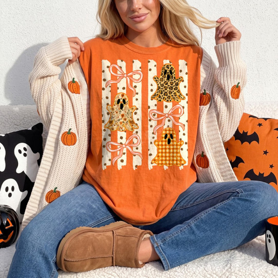Halloween ghost DTF transfer with leopard, floral, and gingham patterned ghosts, pink bows, and polka dot stripes on an orange shirt