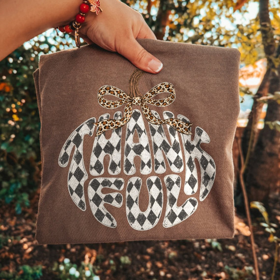 Thankful pumpkin-shaped DTF transfer with black and white checkered lettering and a leopard print bow stem accent