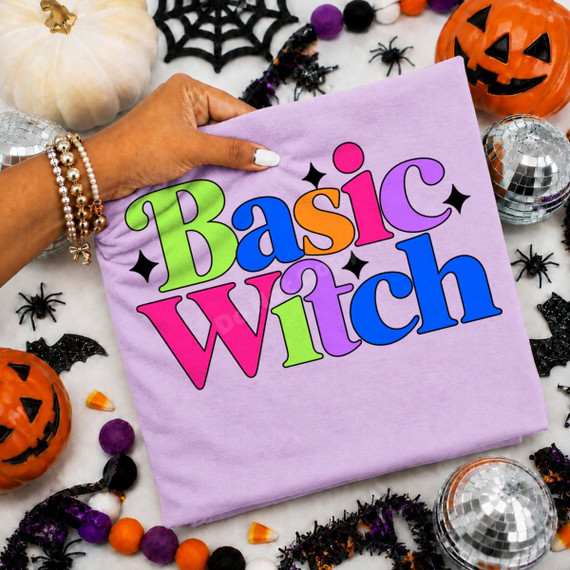 Basic Witch DTF transfer with bold retro rainbow lettering and black star accents on a lavender shirt