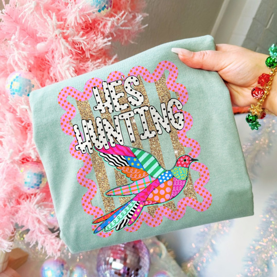 He's Hunting DTF transfer with polka-dot bubble lettering and a colorful multi-pattern bird design on a sage green shirt