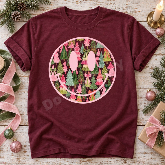 Pink smiley face DTF transfer filled with hand-painted pink, green, teal, and cream Christmas trees and decorative bows Shown on a Wine t-shirt.