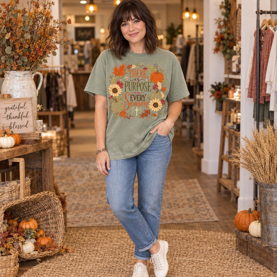 There is Purpose in Every Season faith DTF transfer with autumn wreath of maple leaves, sunflowers, pumpkins, berries, and a small cross Shown on a Sage t-shirt.