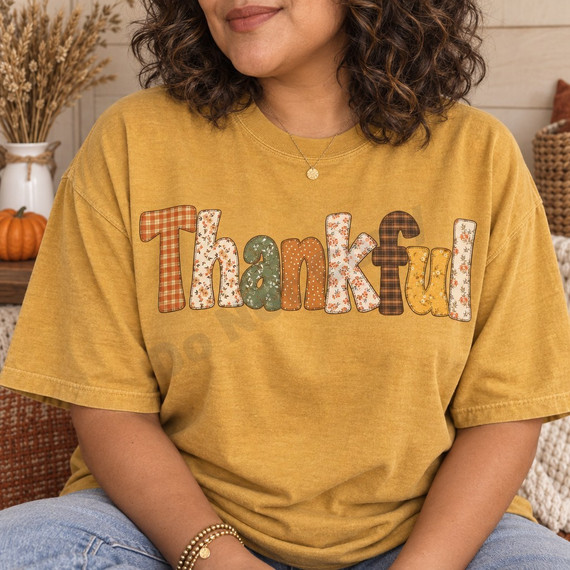 Thankful DTF transfer in oversized block letters with mixed fall plaid, floral, and polka dot patchwork patterns and faux-stitched outline Shown on a Mustard t-shirt.