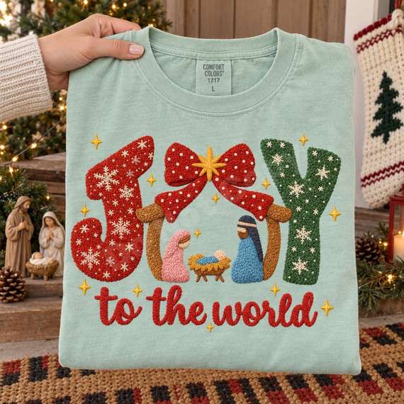 Joy to the World nativity DTF transfer with crochet-textured JOY lettering, red bow, gold star, and manger scene Shown on a Chalky Mint t-shirt.