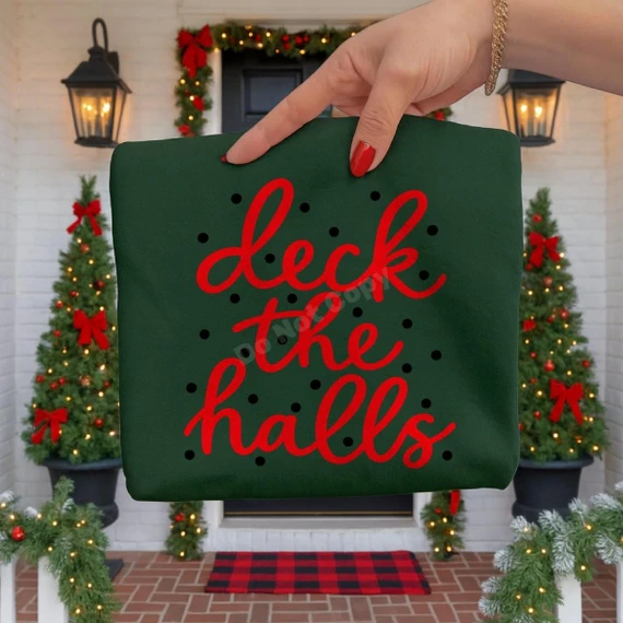 Deck the Halls DTF Transfer | Red Script Christmas Design, red cursive “deck the halls” lettering with black dots displayed on a dark green shirt in front of a festive Christmas porch.