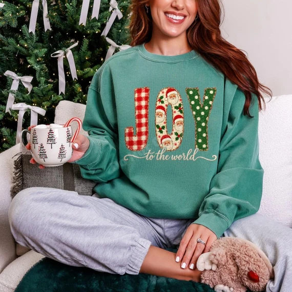 Joy to the World DTF Transfer | Faux Embroidered Santa Christmas Design, faux embroidered-style red and green “JOY to the world” Santa graphic displayed on a teal sweatshirt in a festive Christmas setting