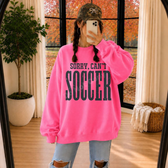 Sorry, Can't Soccer DTF transfer with distressed bold black lettering on a pink sweatshirt