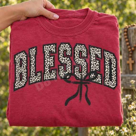 Blessed Leopard Print DTF Transfer | Faith-Based Boutique Design with Cross, leopard-print “BLESSED” lettering with a black cross design displayed on a folded red T-shirt