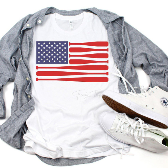 Baseball Flag Sublimation Transfer, white T-shirt with a patriotic American flag design featuring stars and stripes, displayed with a gray shirt, white sneakers, and casual accessories.