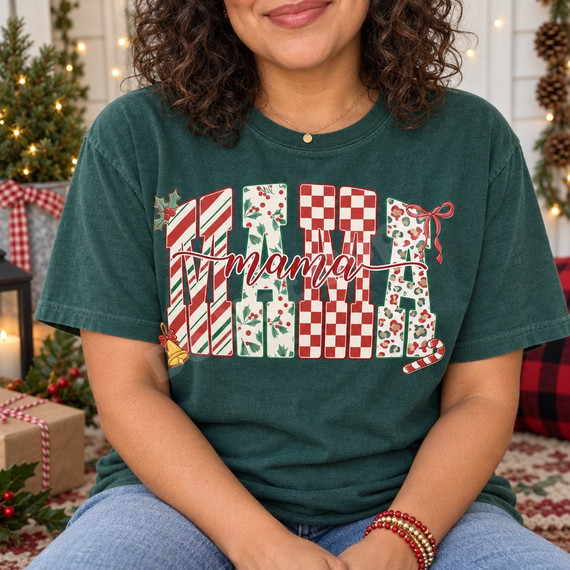 Christmas Mama DTF transfer with chunky block letters filled in candy-cane stripe, holly, checkerboard, and leopard patterns, topped with red cursive mama script and holiday bow, bell, and candy cane accents Shown on a Blue Spruce t-shirt.