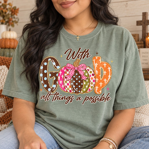 With God All Things Are Possible fall DTF transfer featuring a polka-dot G, patterned pumpkins forming the O with a pink gingham bow, and a cross-patterned D Shown on a Sage t-shirt.