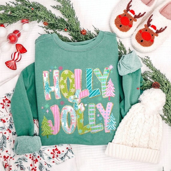 Holly Jolly Christmas DTF transfer in colorful pastel patterned lettering with mini Christmas trees and snowflakes on a green sweatshirt
