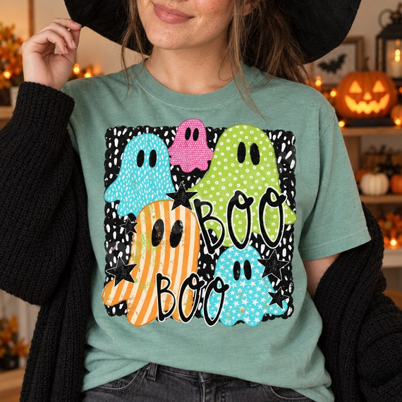 BOO Halloween DTF transfer featuring five patterned cartoon ghosts in teal, pink, green, and orange on a black and white speckled background with stars Shown on a Seafoam t-shirt.