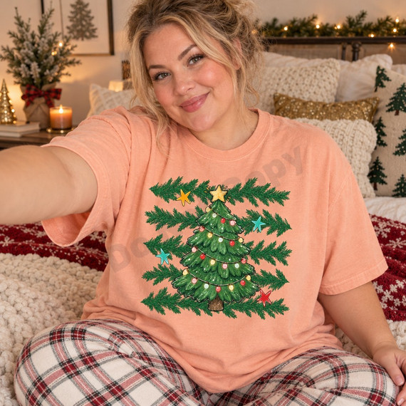 Hand-illustrated Christmas tree DTF transfer with glowing string lights, colorful ornaments, a gold star topper, pine branches, and scattered gold, teal, and red stars Shown on a Peachy t-shirt.