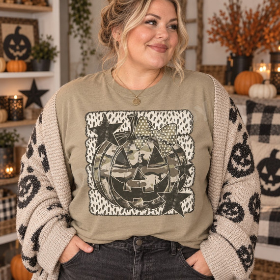 Distressed camouflage jack-o-lantern DTF transfer with polka-dot bow and charcoal stars on a textured dot-print background Shown on a Khaki t-shirt.